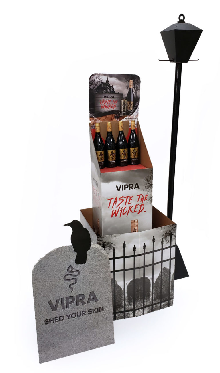 Wine bottle display with corrugated lamp, gravestone, and printed fence wrap