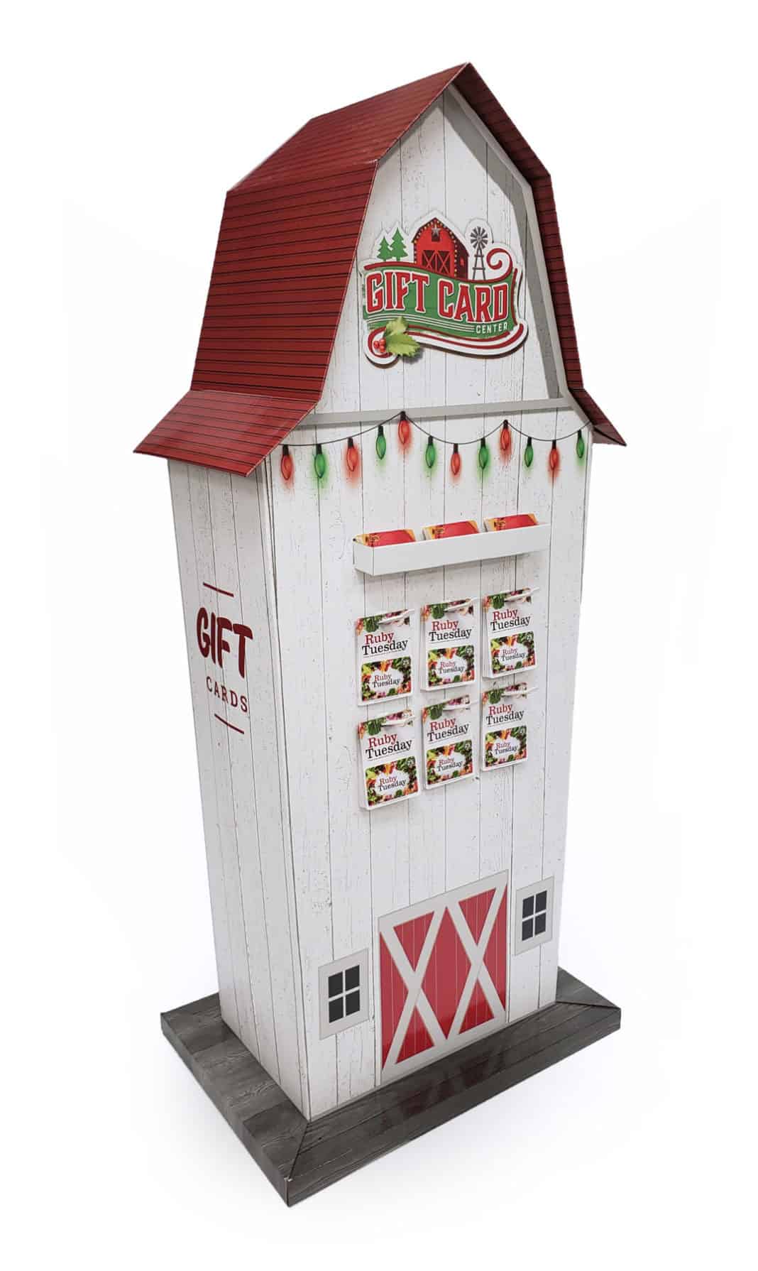 Tall giftcard display shaped like a white barn with a red roof